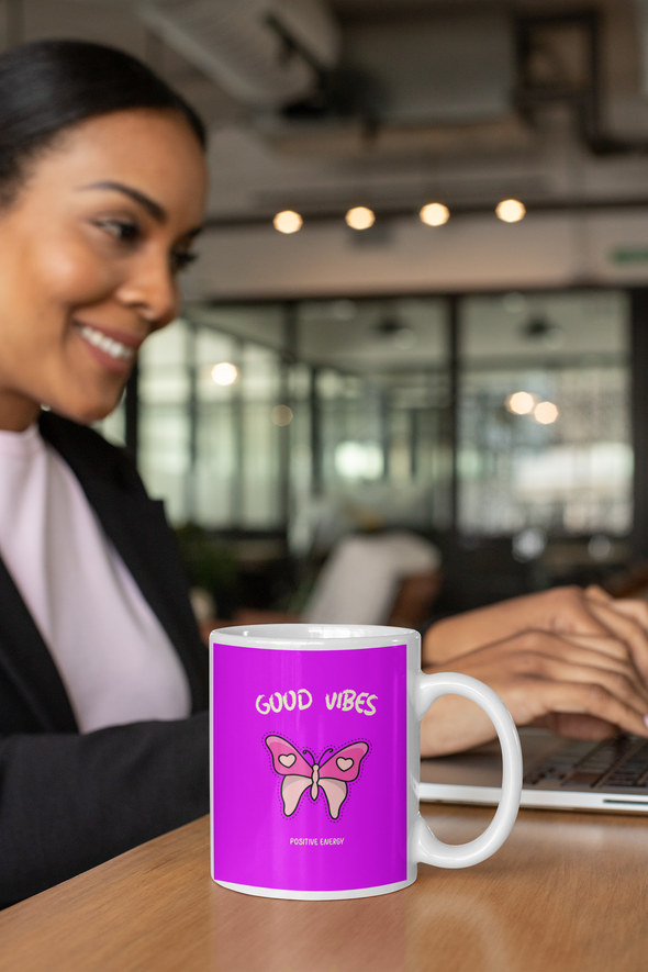 woman working on laptop computer with coffee mug nearby that reads GOOD VIBES POSITIVE ENERGY