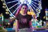 black T-shirt says LIVING my best LIFE worn by attractive brunette at amusement park at night