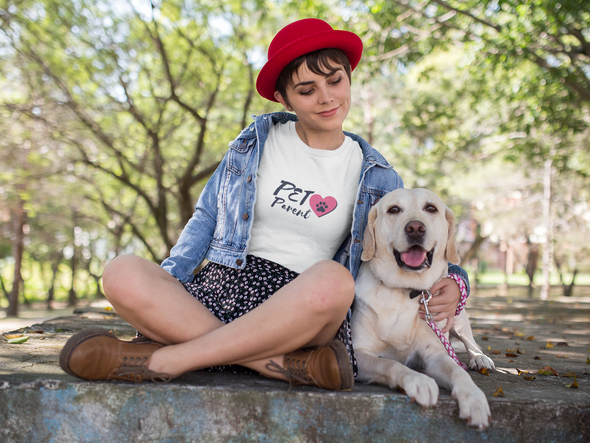Young woman sitting in park with her dog wearing PET Parent t-shirt