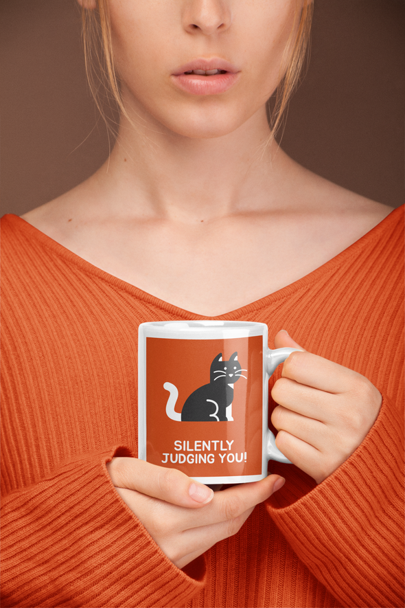attractive woman wearing orange sweater holding coffee mug with cat that says SILENTLY JUDGING YOU