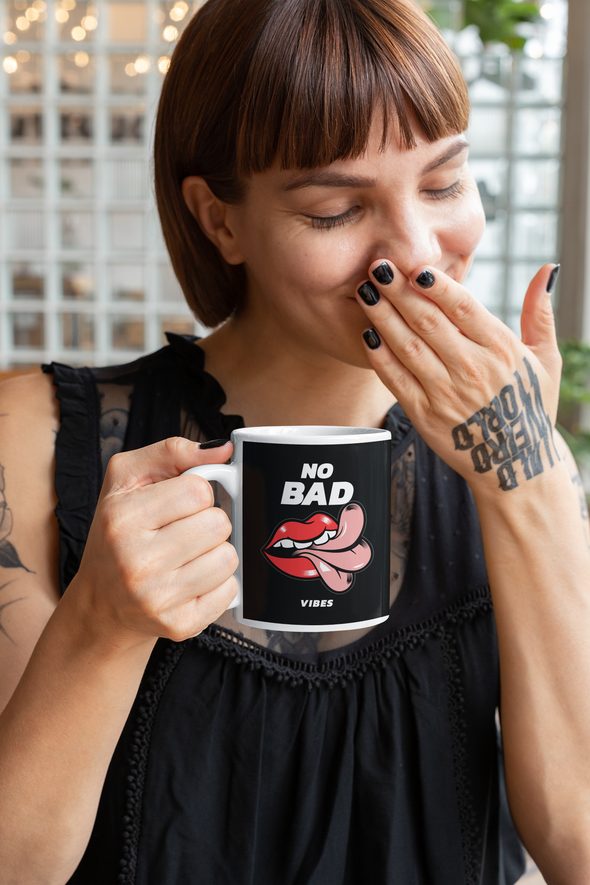 tattooed woman holding a coffee mug that says NO BAD VIBES