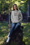 attractive woman sitting on a log in the woads wearing a hoodie that says I love my job