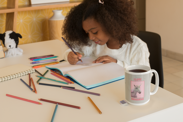 little girl with coloring book and coffee mug that says I LOVE UNICORNS