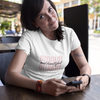 woman wearing a t-shirt that says STRONG AND BEAUTIFUL sitting at a coffee shop with her smart phone